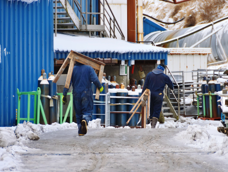 Two workers at a construction site in the winter carry materials. Prevent frozen water pipes.
