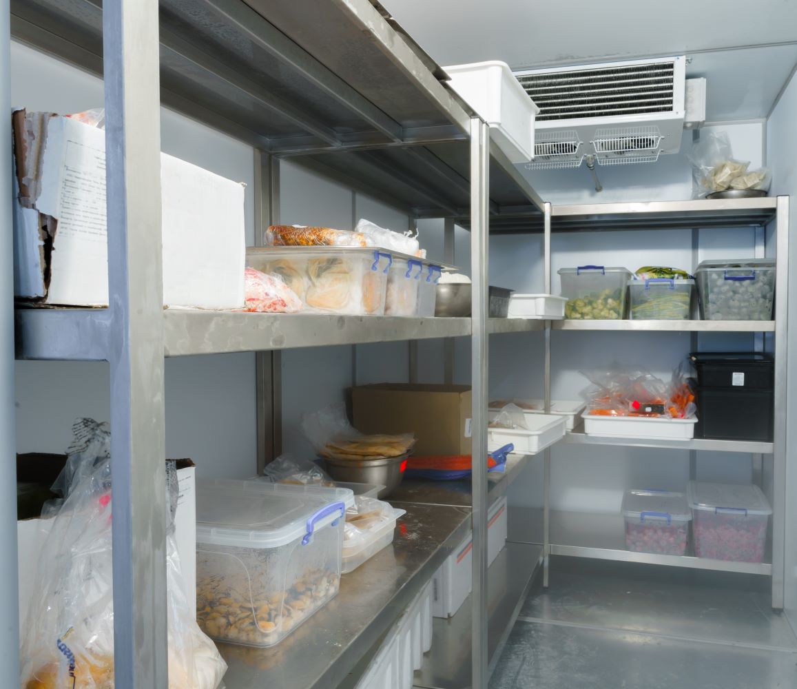 Commercial restaurant walk-in cooler with bins of food on shelves. This is an ideal application for a Commercial refrigeration temperature monitoring, walk in cooler temperature sensor, or freezer temperature alarm system.